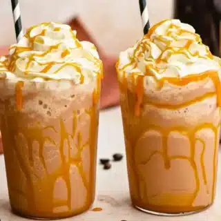 Two caramel drinks with straws and whipped cream