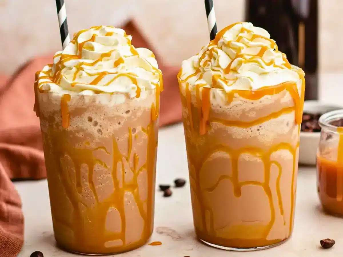 Two caramel drinks with straws and whipped cream