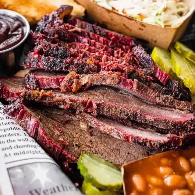 close up of brisket with bbq sauce, baked beans and coleslaw