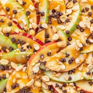 Sliced apples plated fanned out with caramel and toppings close up