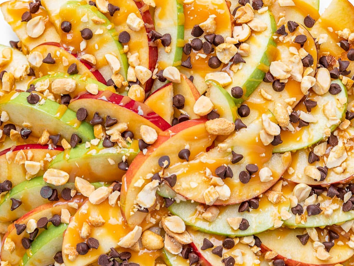 Sliced apples plated fanned out with caramel and toppings close up