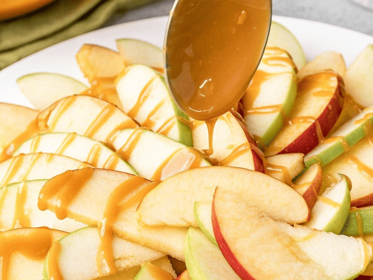 drizzling caramel over apple slices on plate