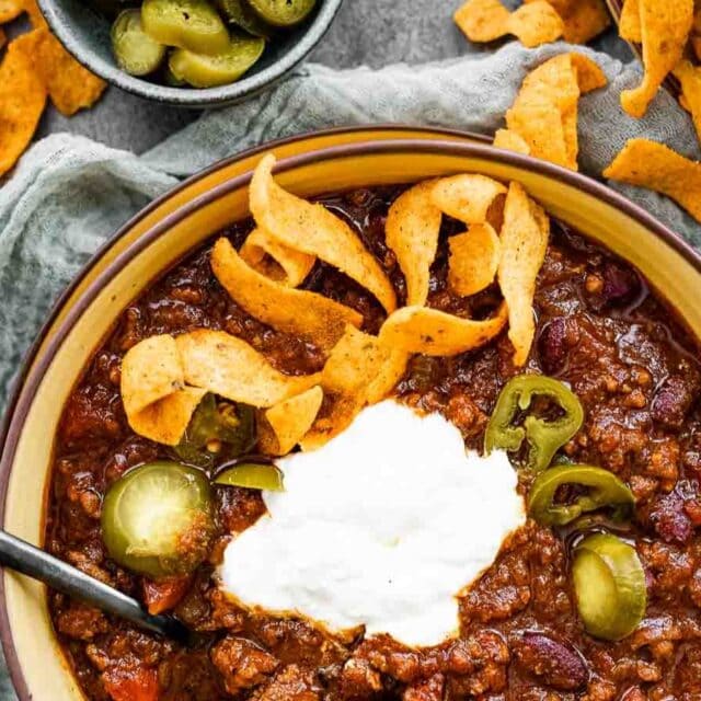 Bowl of chili with sour cream chips and jalepenos