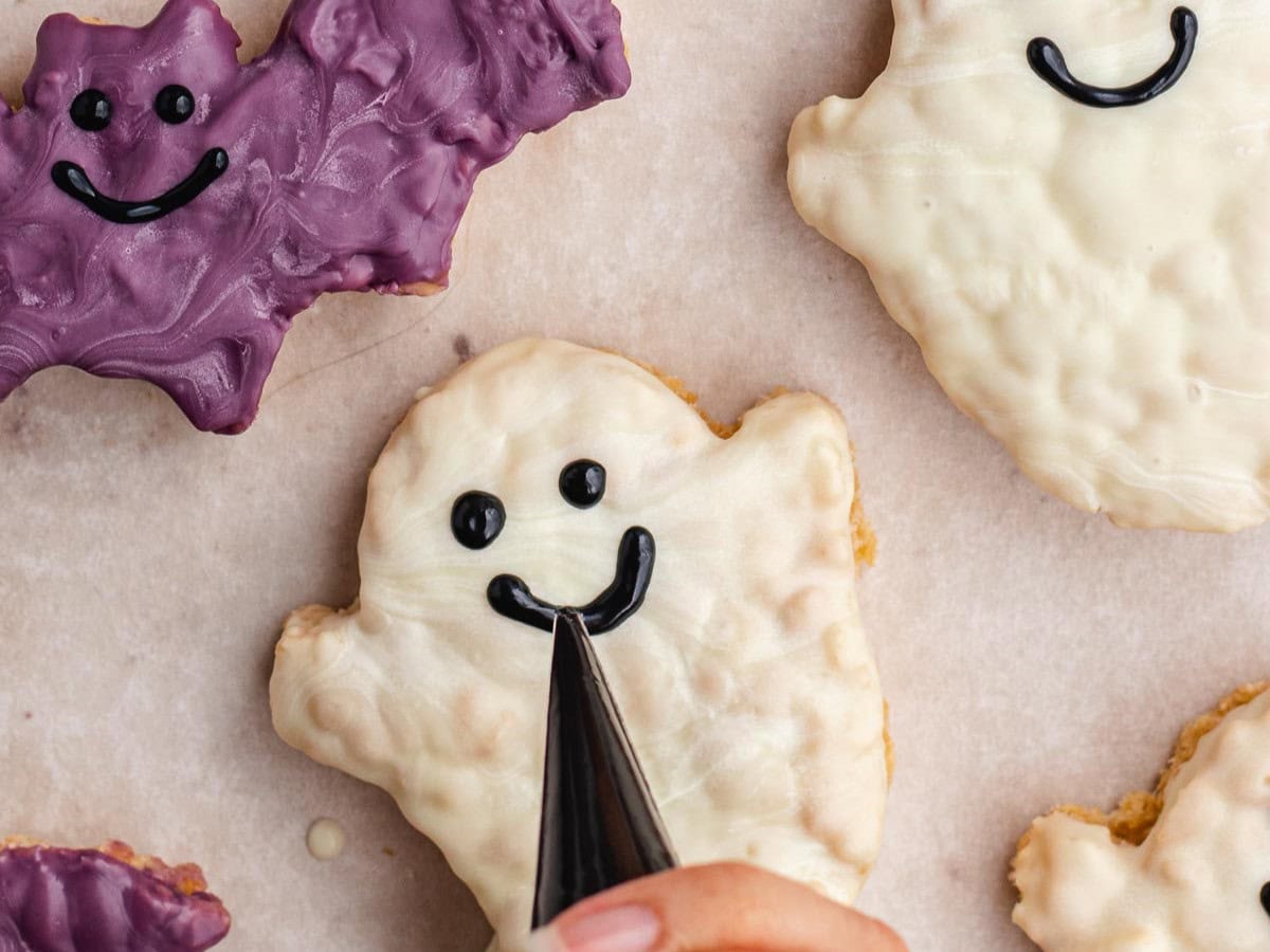 Piping a face onto ghost shaped treat