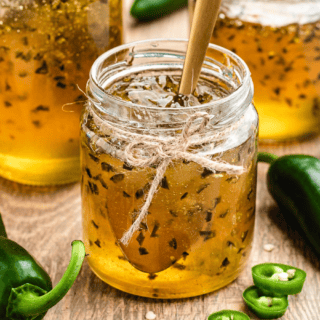 jelly in a jar with a spoon in it with jars in background