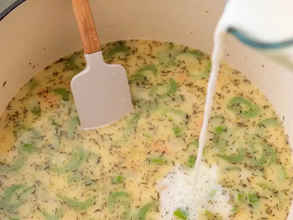 pouring cream into pot of ingredients