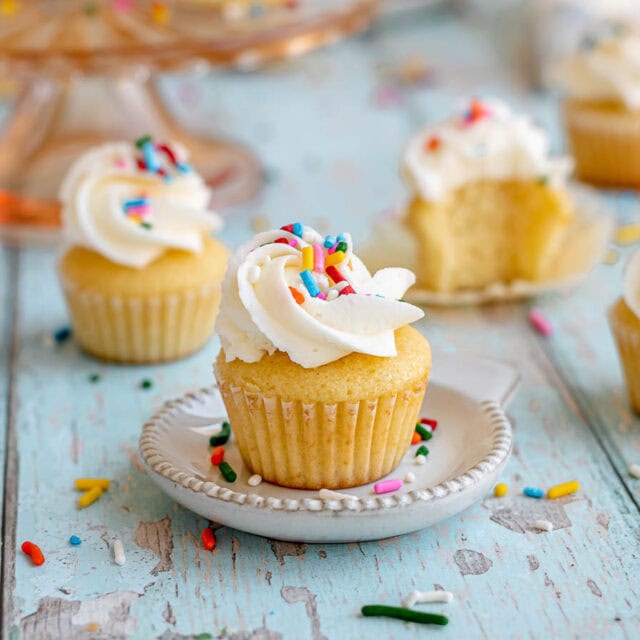 Mini cupcake on a plate with sprinkles.