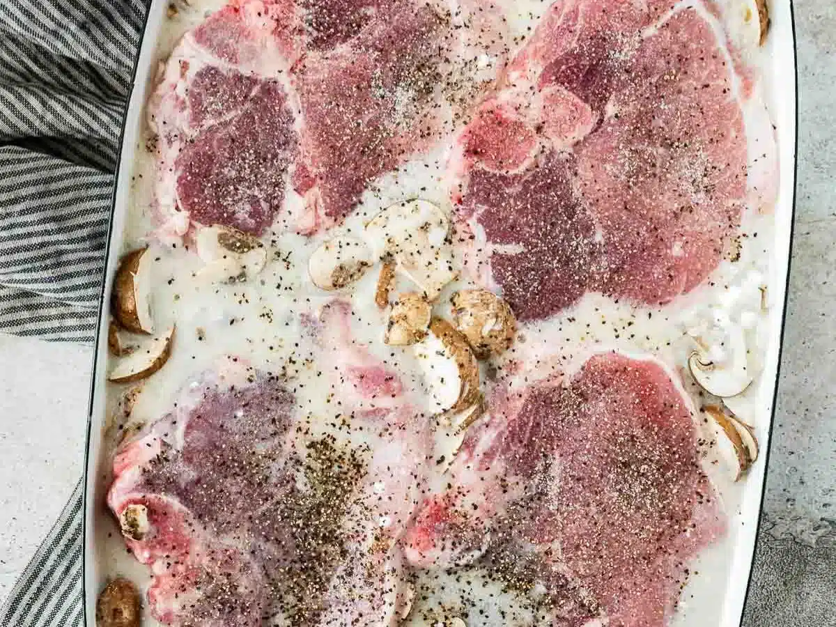 Raw pork, condensed soup, mushrooms, and rice in baking dish.