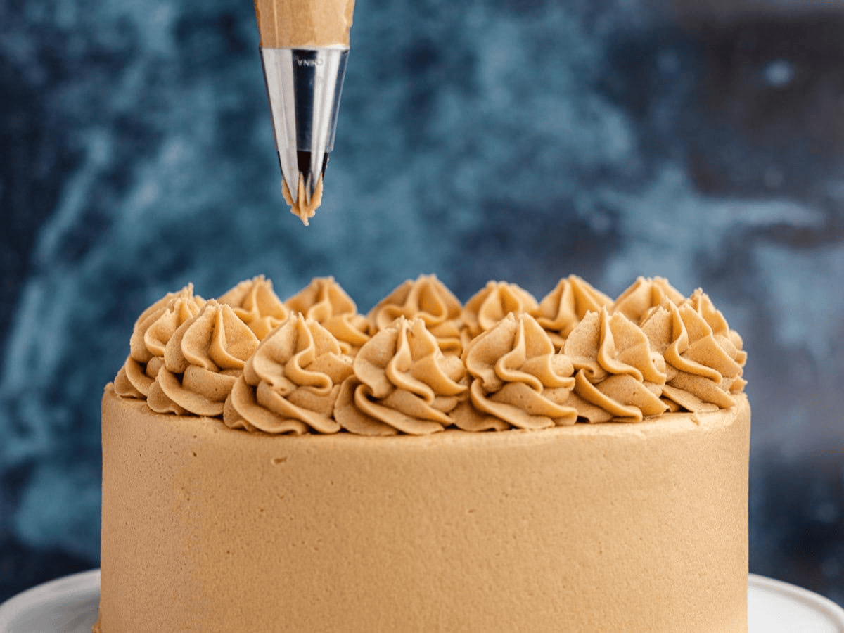 Piping caramel frosting on a finished cake