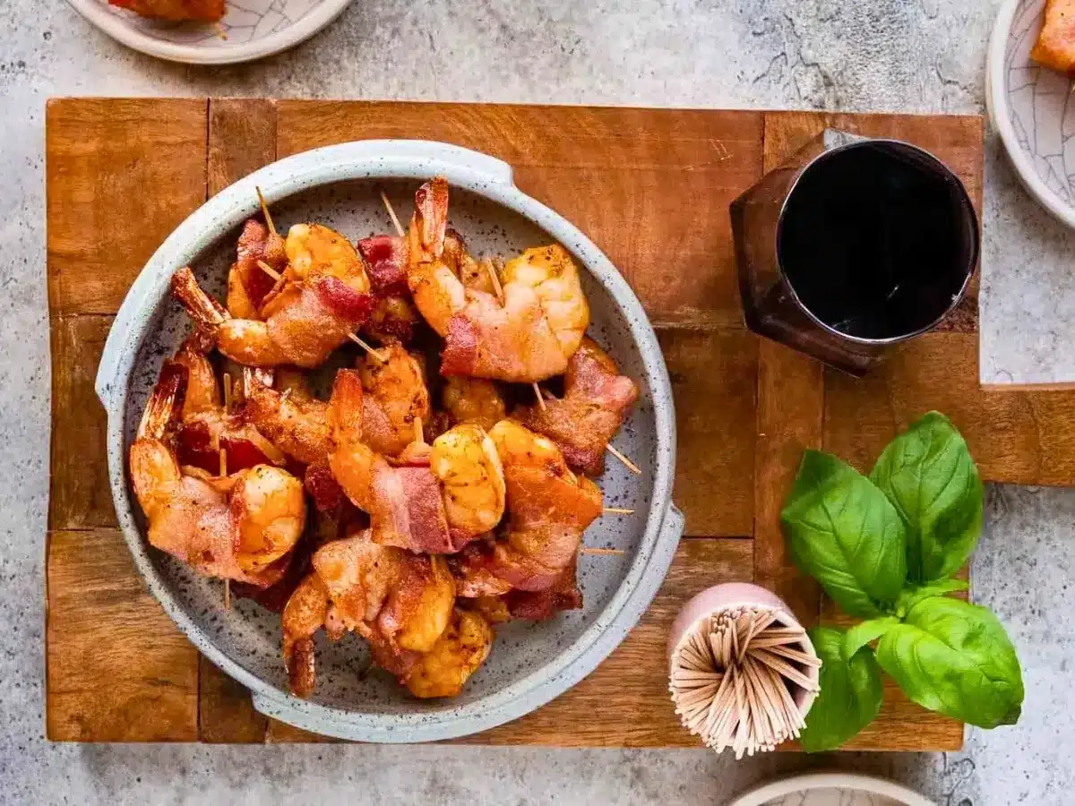 Bowl of shrimp wrapped in bacon on cutting board