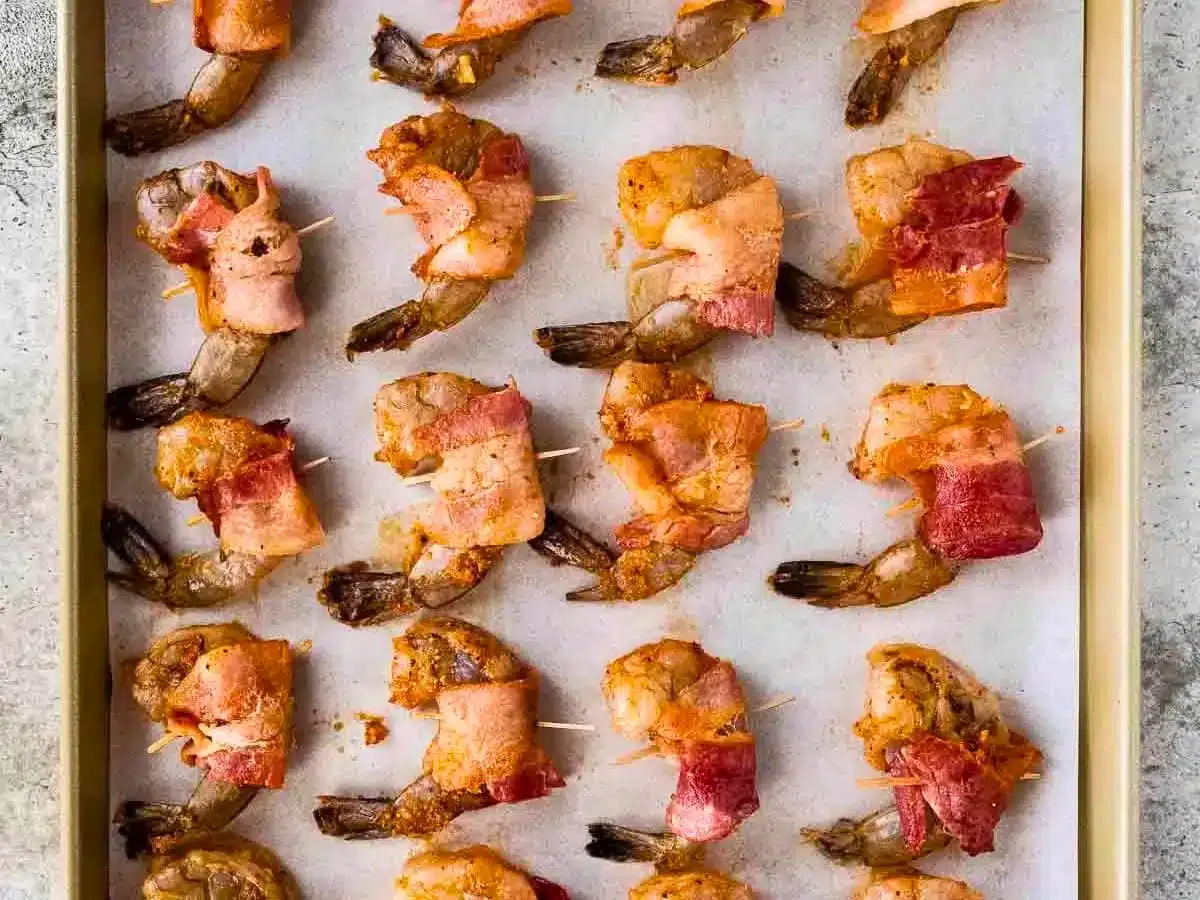 Precooked shrimp wrapped in bacon on baking sheet