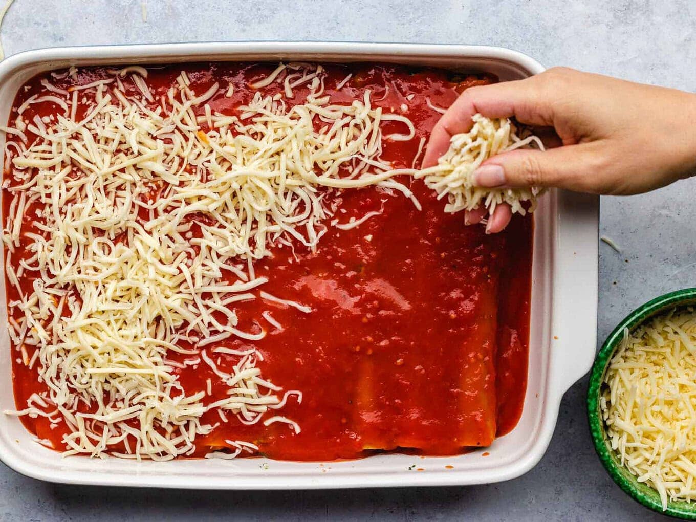 cheese being added to top of dish by hand 