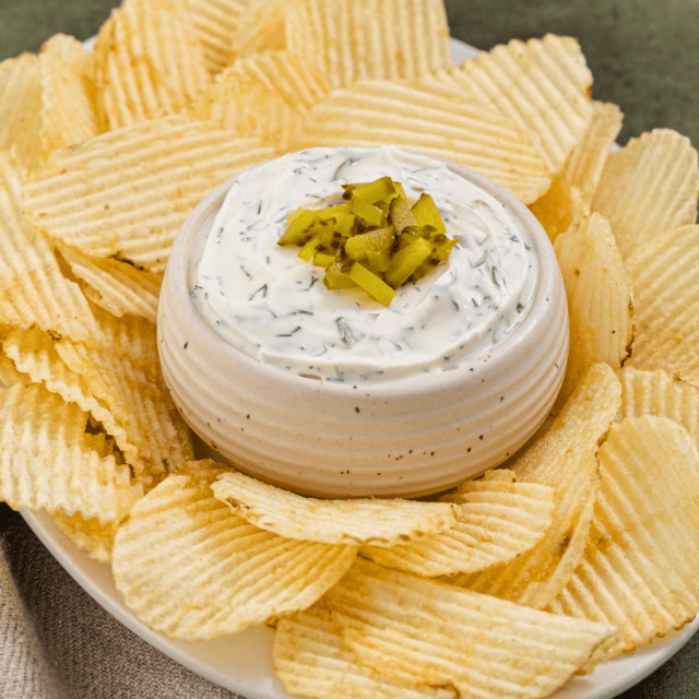 Bowl of pickle dip with chips around it