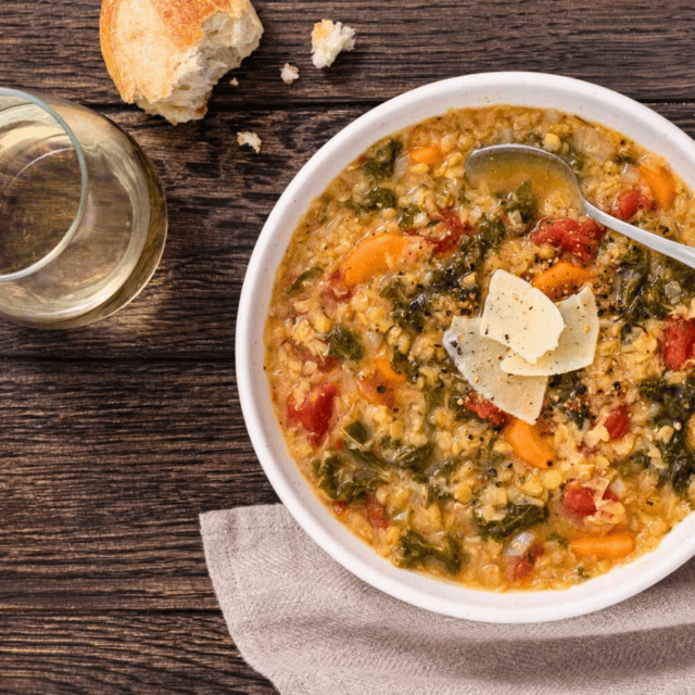 soup in a bowl with spoon, glass, and bread