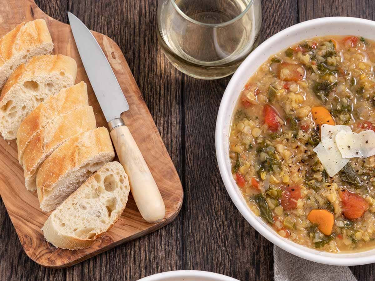 Sliced bread on a cutting board next to a bowl of soup