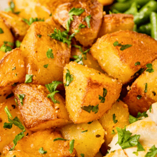 close up of seasoned cubed potatoes with green garnish