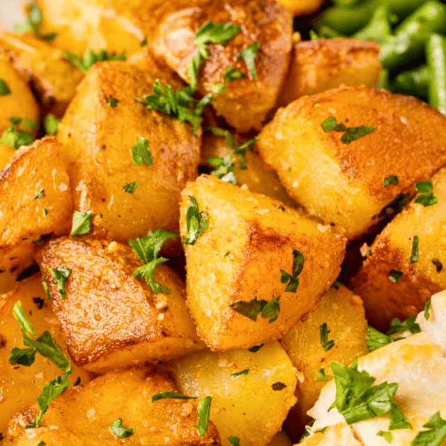 close up of seasoned cubed potatoes with green garnish