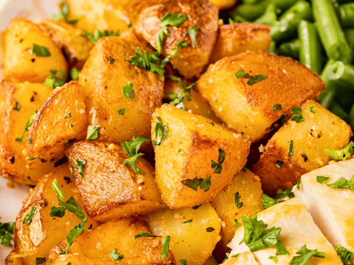 close up of seasoned cubed potatoes with green garnish
