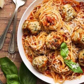 Cooked meatballs with spaghetti in bowl with basil