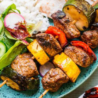 Beef and veggie kabobs on dinner plate with rice and salad 4x3