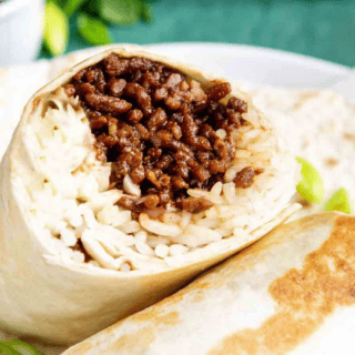 Beef and rice wrapped in a tortilla on a white plate.