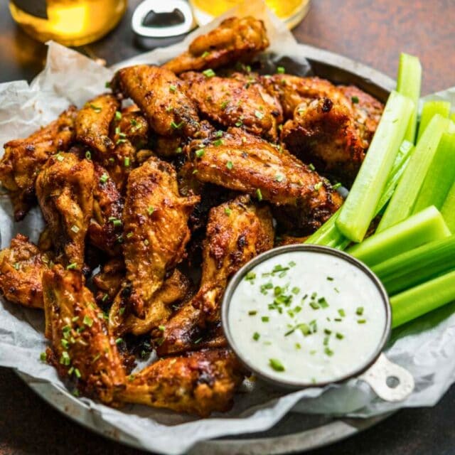 Cooked wings in a basket with ranch and celery sticks
