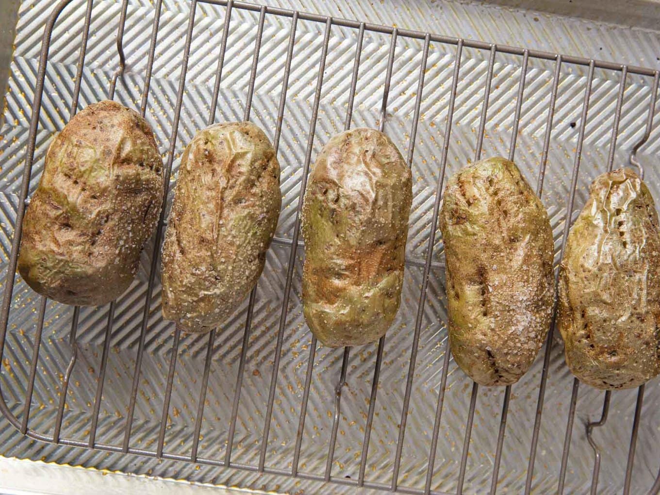 Baked Potatoes every time for crispy outside tender inside potatoes. #dinner #sidedish #potato #bakedpotato #dinnerthendessert Baked russet potatoes lined up on baking rack