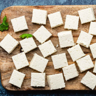 Paneer cut up in squares on wooden board