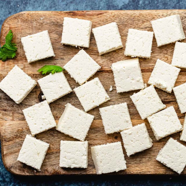 Paneer cut up in squares on wooden board