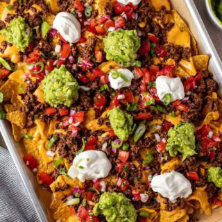 Baking sheet of finished nachos with toppings