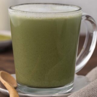 Tea latte in clear mug with wooden spoon on side