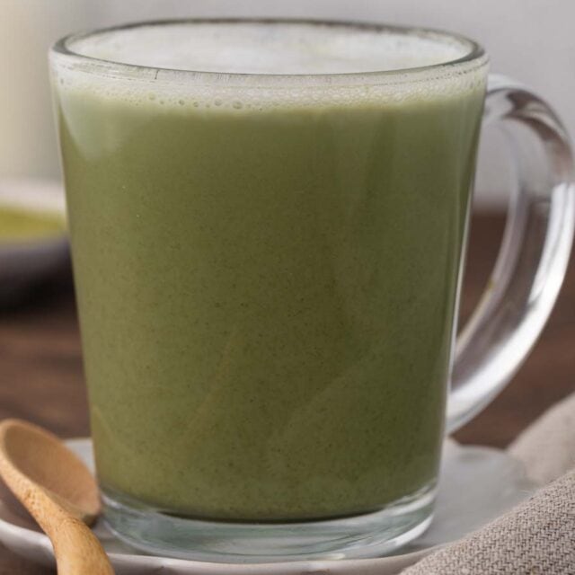 Tea latte in clear mug with wooden spoon on side