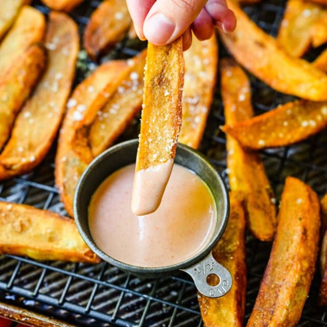 Cooked fries on rack and dipping fry in sauce