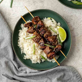 Plate with rice topped with 2 beef skewers