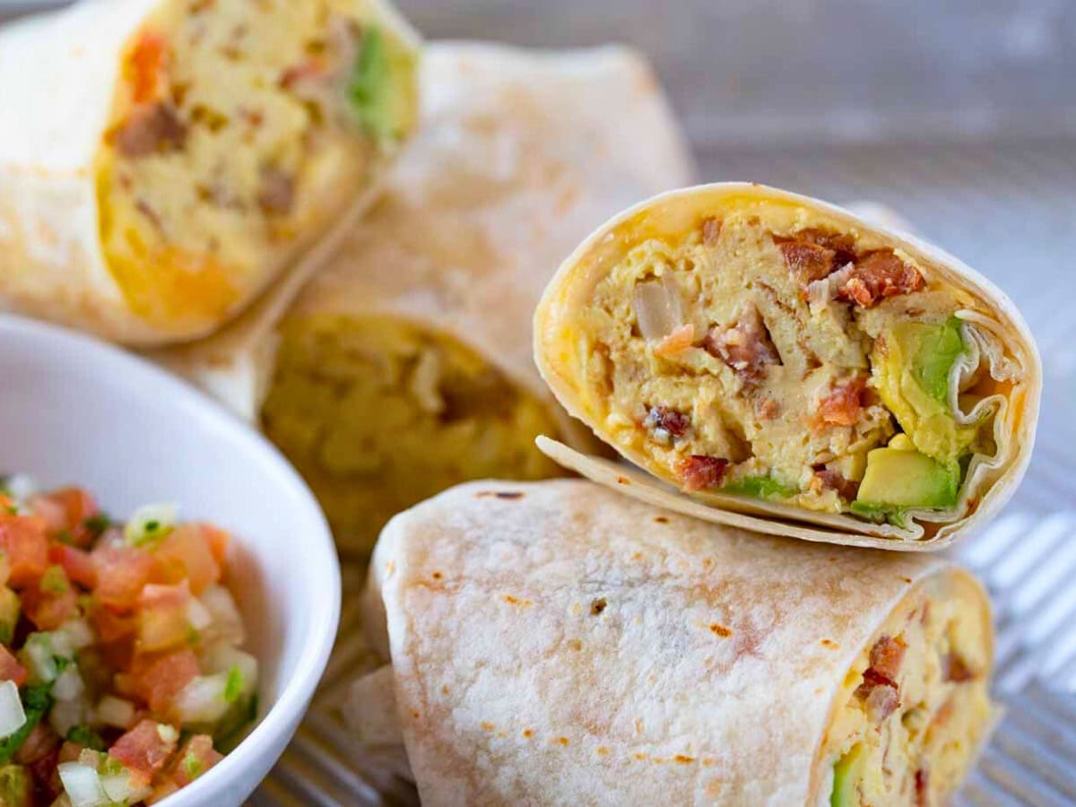 Halved burritos stacked on a platter with pico de gallo