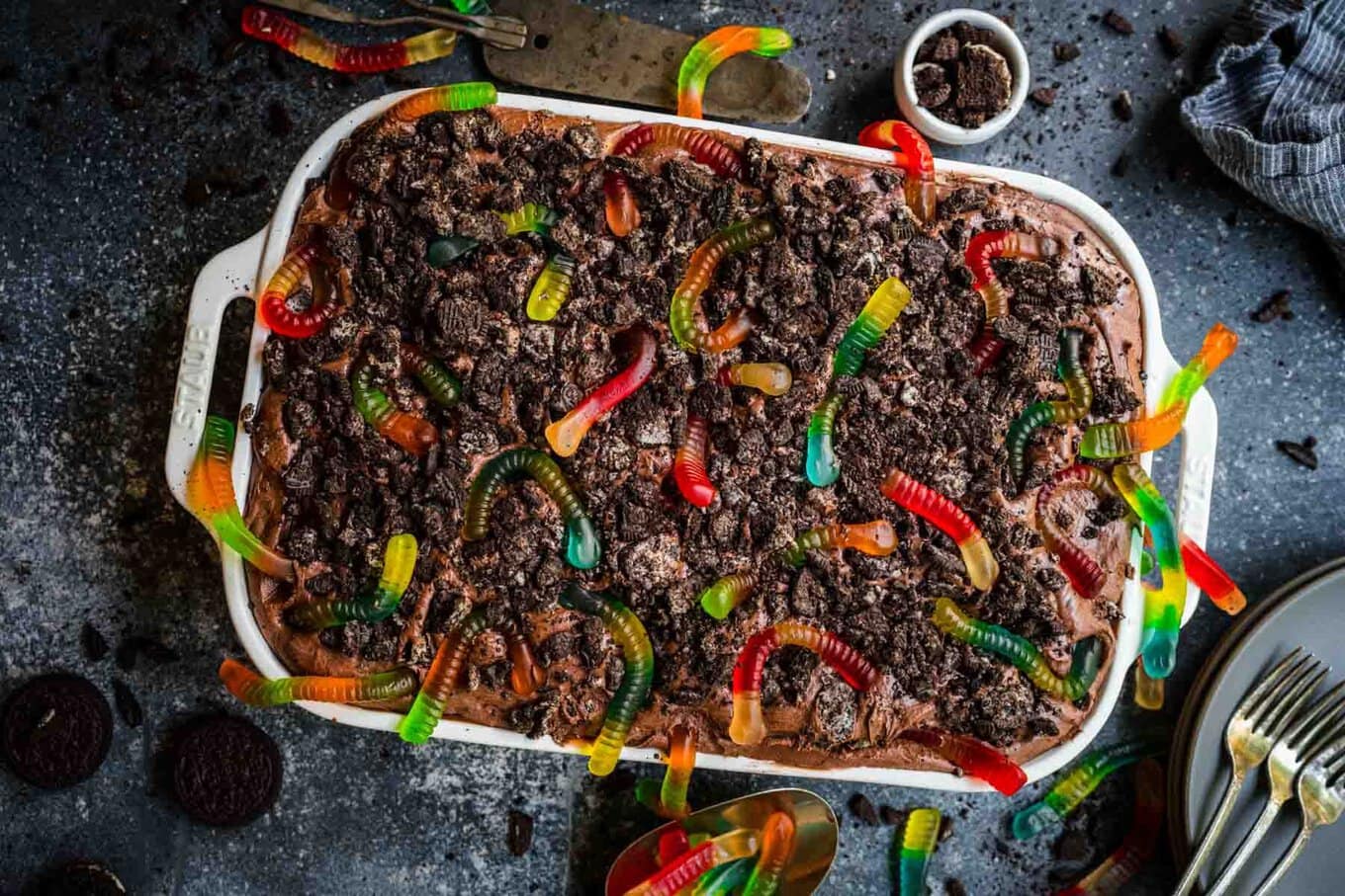 Chocolate Pudding Dirt Cake with pudding, crushed oreos, and gummy worms on top in baking dish