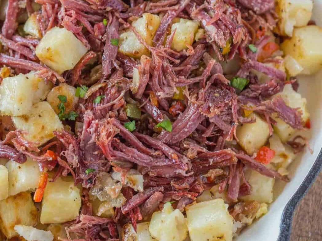 Close of up of cooked beef and potatoes in pan