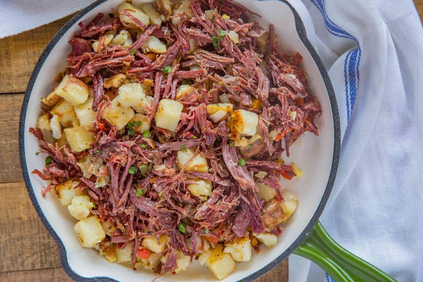 Corned Beef Hash is a CLASSIC breakfast made with homemade corned beef, diced potatoes, and onions, ready in under 15 minutes! #homemade #cornedbeef #brunch #breakfast #easy #leftovers #stpatricksday #fromscratch #dinnerthendessert Zoomed out photo of cooked hash in skillet