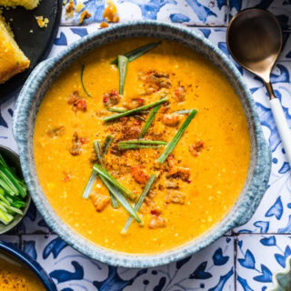 Soup with garnish and crawfish with bowls of onion and cornbread slice
