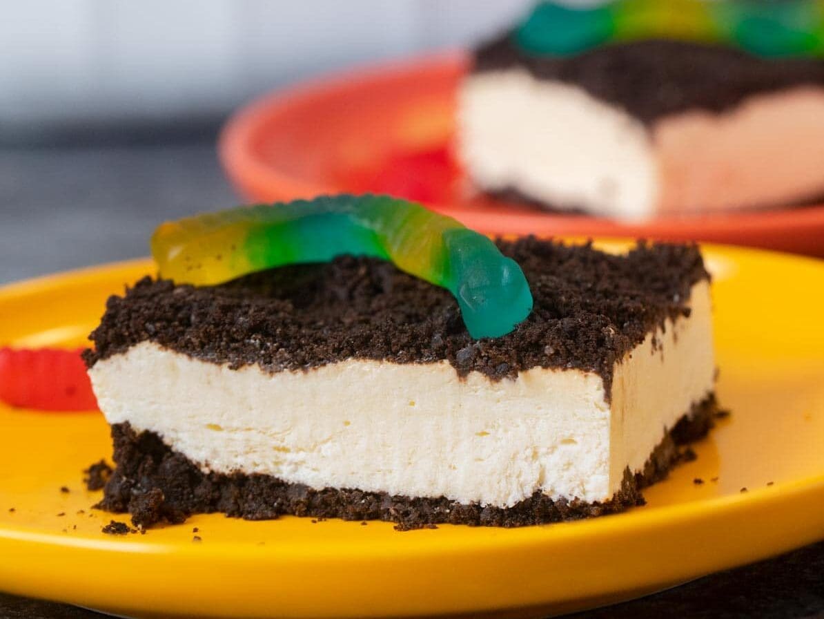 Serving of cake with gummy worm on yellow plate