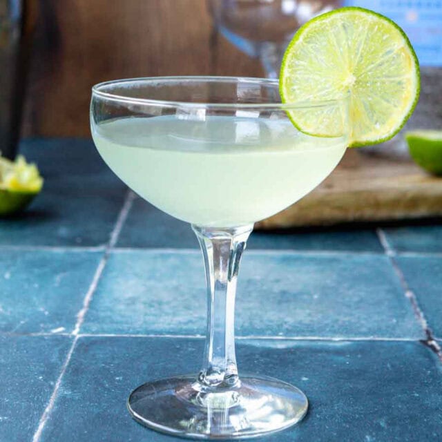Closeup side view of cocktail in coupe glass with lime slice