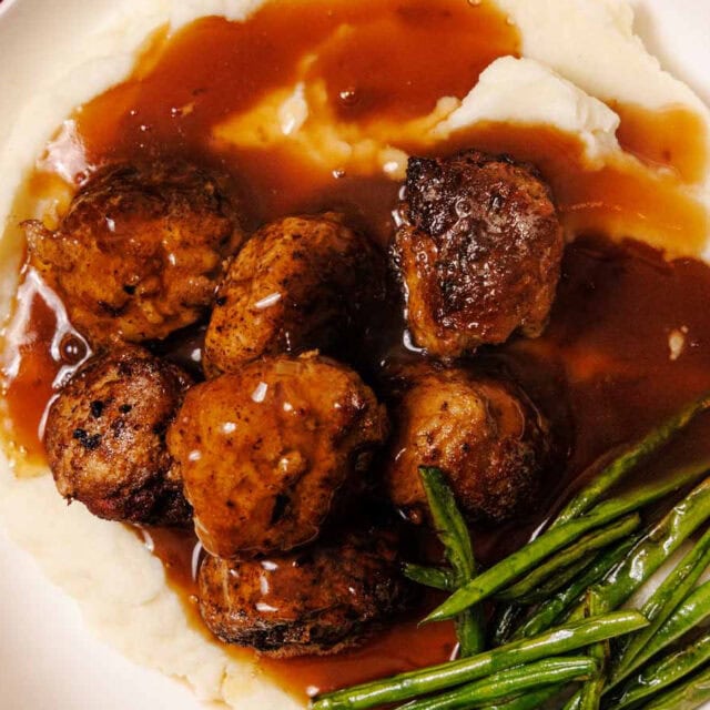 Plated meatballs with sauce, mashed potatoes and green beans