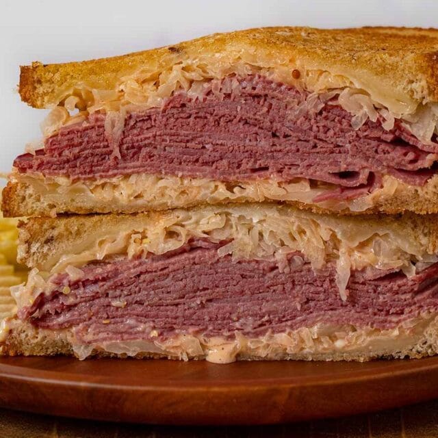 Reuben Sandwich halves in stack on plate with chips