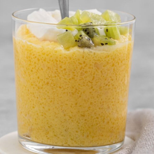 Pudding in a glass with kiwi, whipped cream and spoon