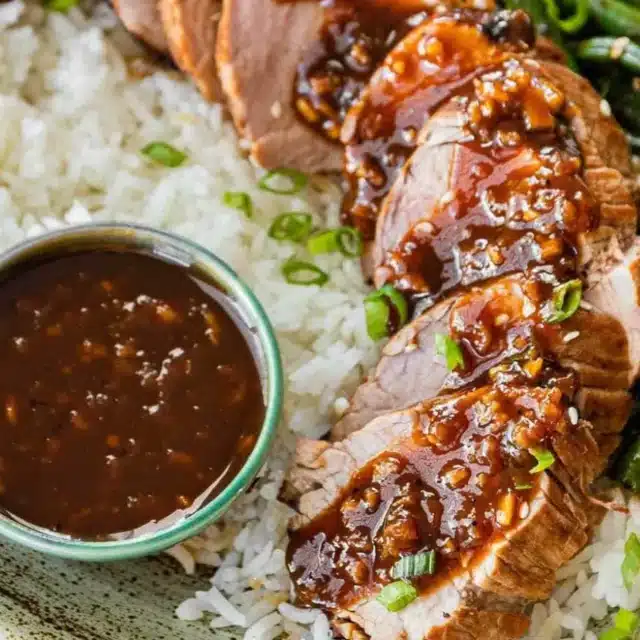 Pork served with rice and sauce on plate