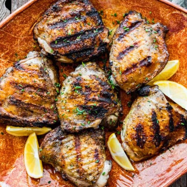 Grilled chicken thighs on serving plate.