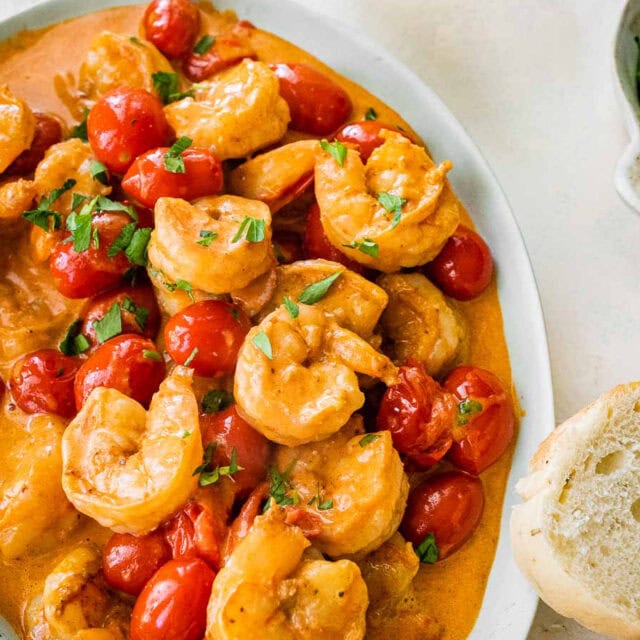 Bowl with shrimp in sauce and bread on side