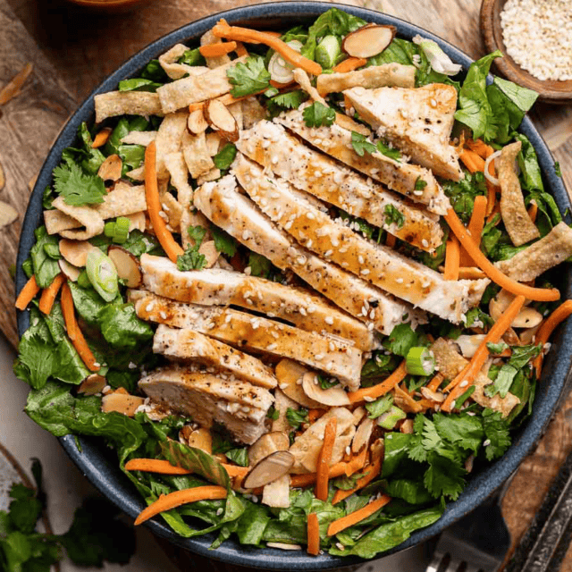 Green salad with sliced chicken breast on top, on dinner plate.