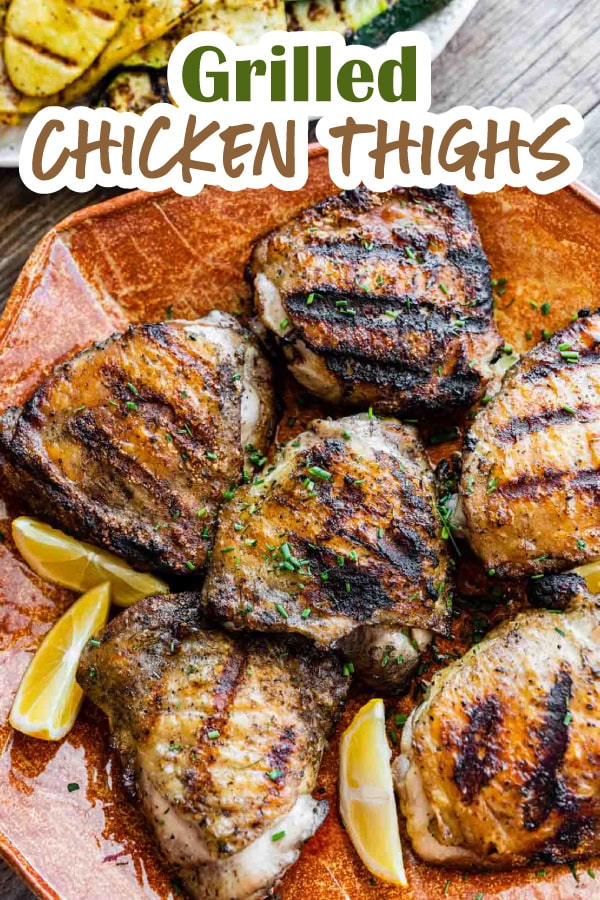 Platter of grilled chicken pieces with lemon wedges