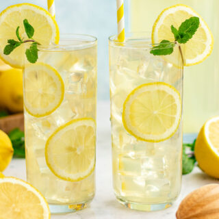 Two tall glasses of lemonade with lemon slices and mint sprigs